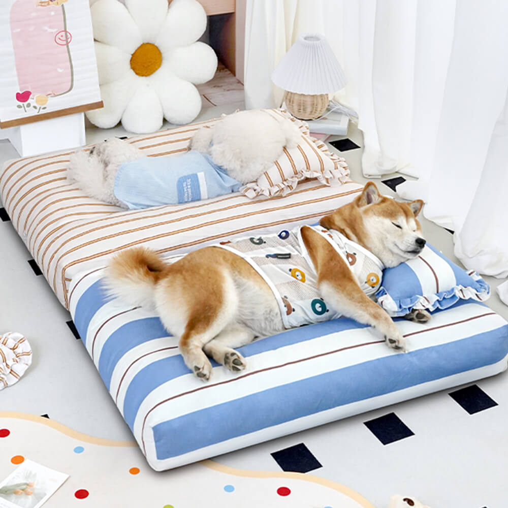 A small dog curled up on a striped cotton dog bed with thick padding.
