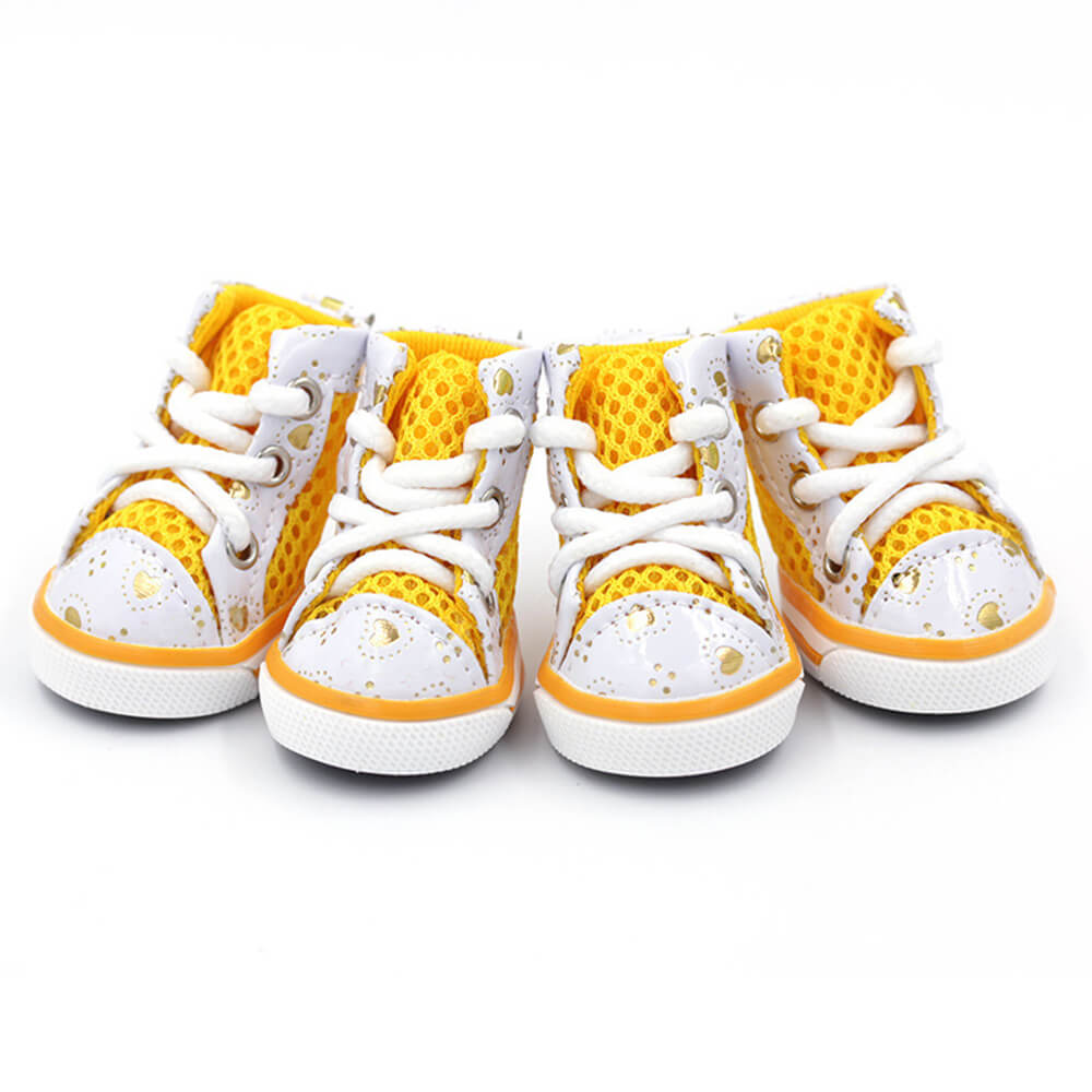 A small dog wearing black mesh dog shoes, standing on a grassy path, showcasing the high-top design and secure fit.