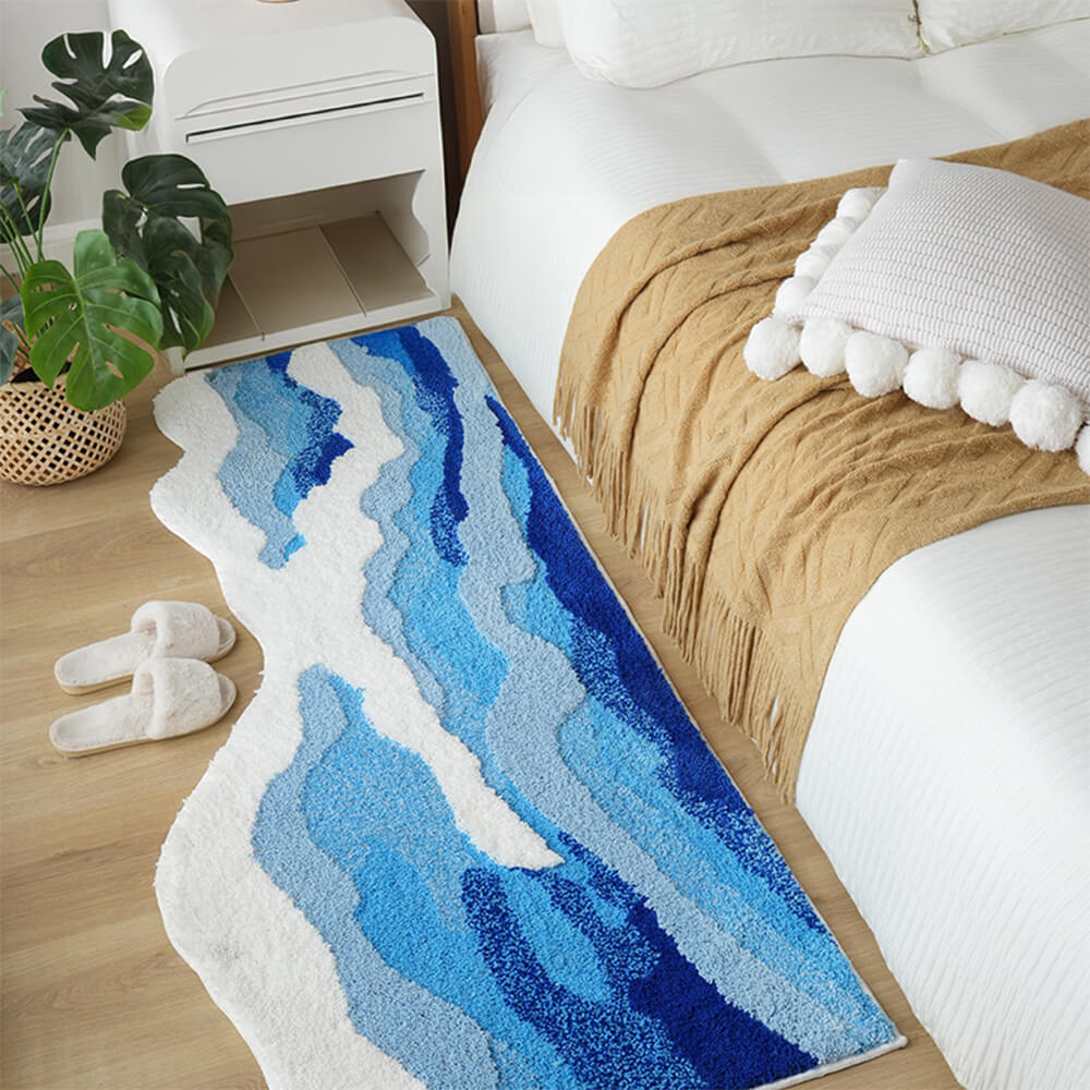 Top-down view of hand-tufted carpet showcasing its wave-inspired 3D texture in soft coastal tones.