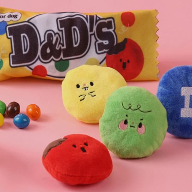 A close-up view of the Whimsical Treat Bag dog puzzle toy, showing the main snack bag with colorful 'candy beans' peeking out, hinting at hidden treats and interactive features.