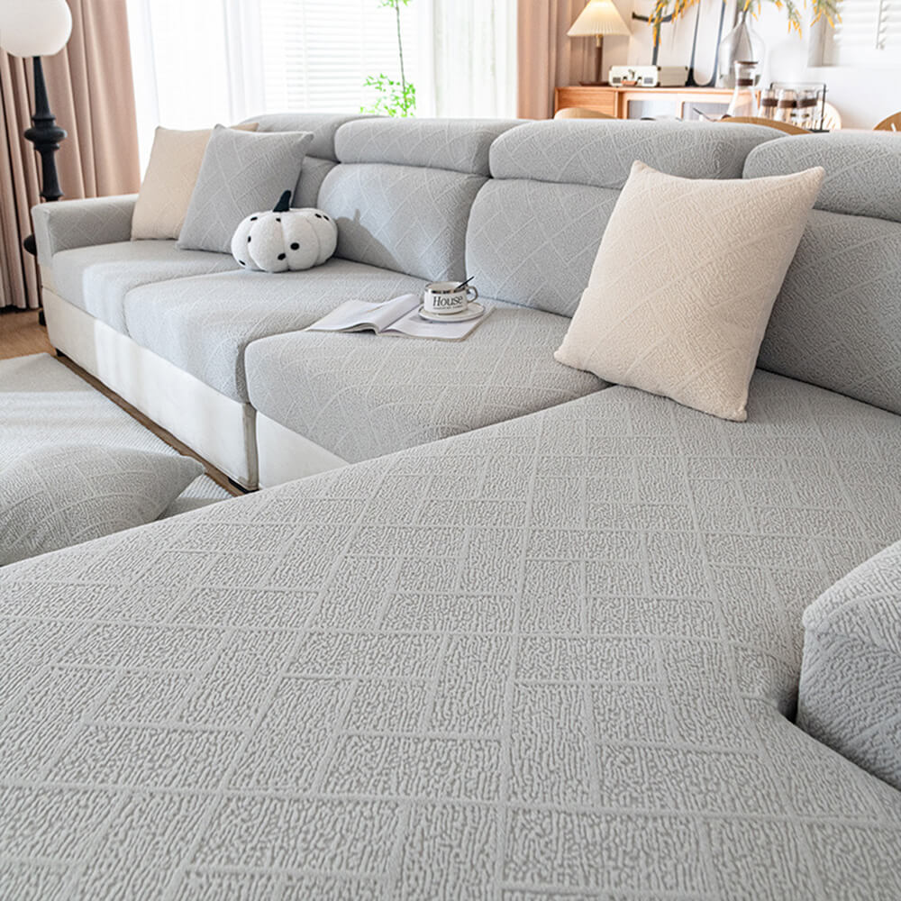 Diamond Jacquard sofa protector draped over a modern gray couch