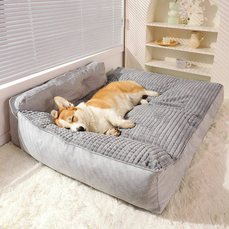 A large, plush grey orthopedic dog bed with a raised pillow section, showing its soft texture and generous size, perfect for a comfortable rest.