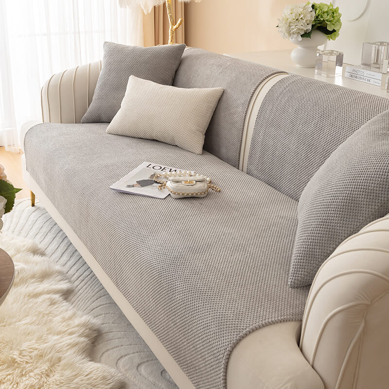 Angled view of plush furniture cover protecting a gray sectional sofa, highlighting the soft texture and tailored fit