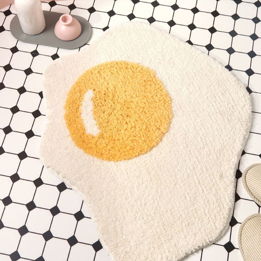 Close-up of the fried egg shaggy bath mat showing its plush texture and playful design