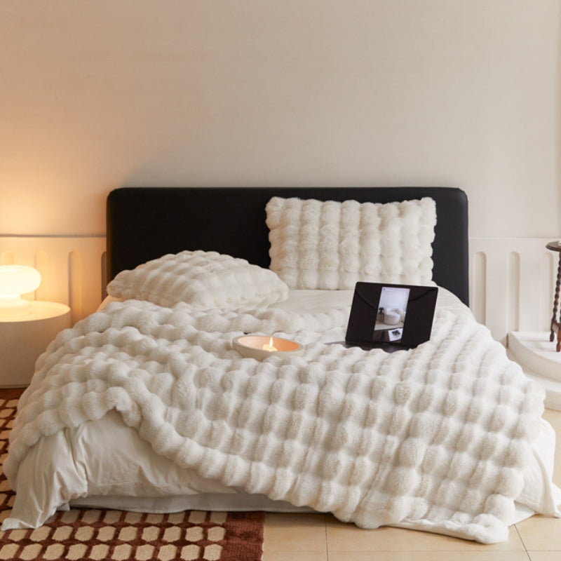 CozyLux Faux Rabbit Fur Throw Blanket on a couch, showcasing its plush texture and luxurious design