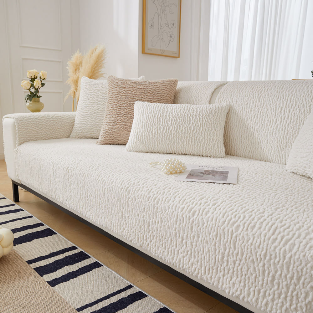 Cream-colored Berber fleece sofa protector draped over a couch, showing non-slip underside.
