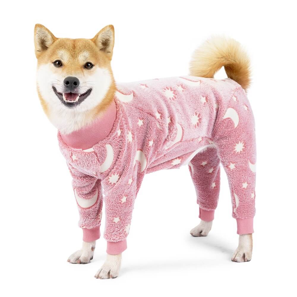 A small dog wearing blue Celestial Cozy Moon & Stars dog pajamas, lying comfortably on a soft blanket, showcasing the cute sleepwear design.