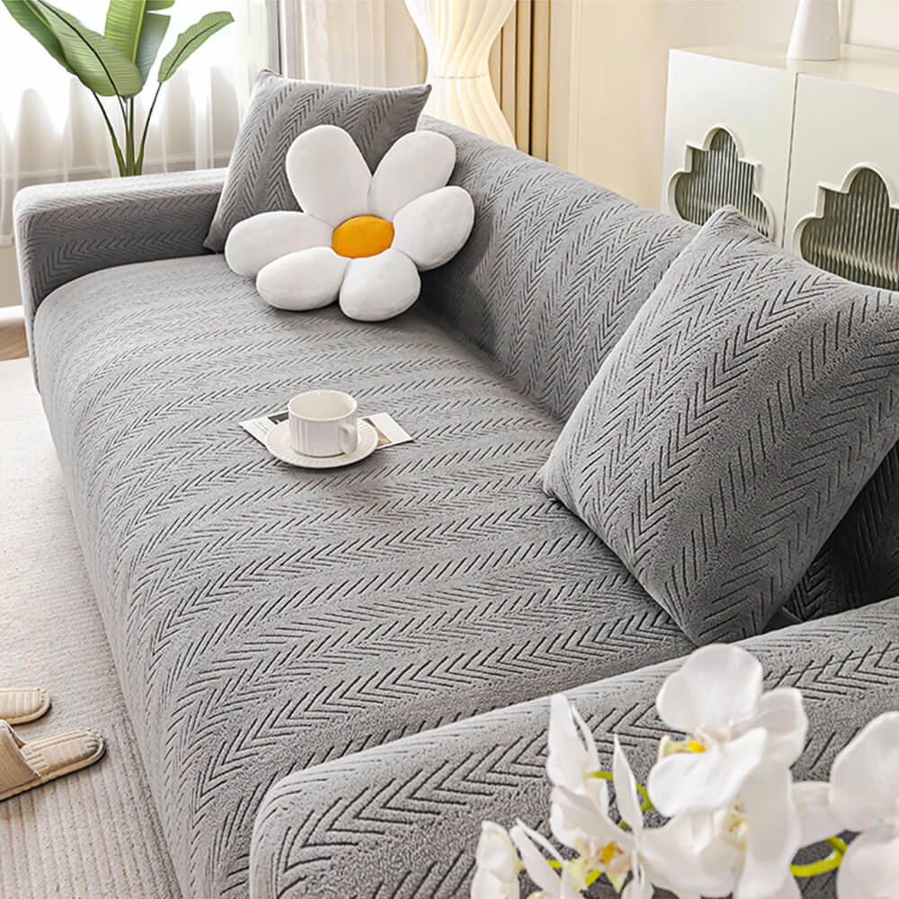 A cream herringbone stretch couch cover elegantly fitted on a modern sofa, showcasing its snug fit and textured design.