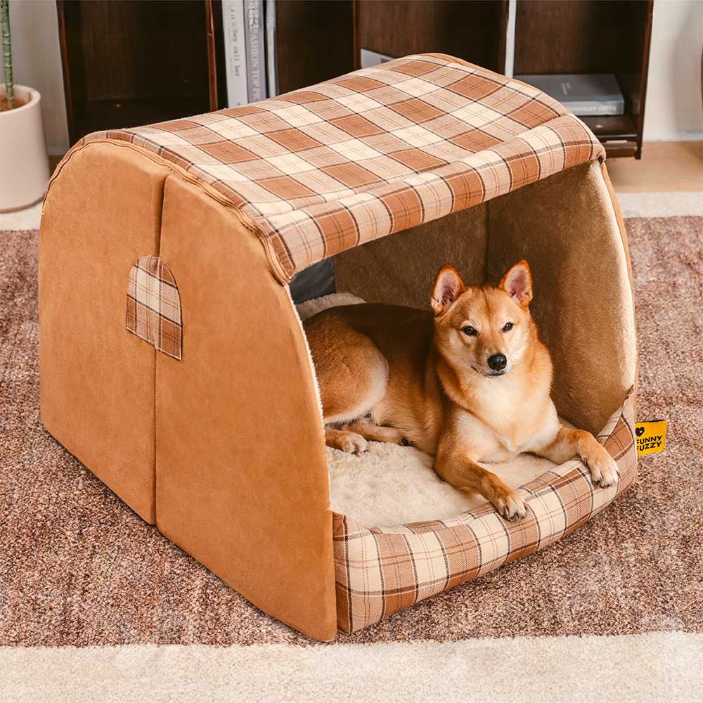 A golden retriever comfortably resting inside a large orthopedic pet bed with a cozy plaid design, showcasing the plush interior and house-like structure.