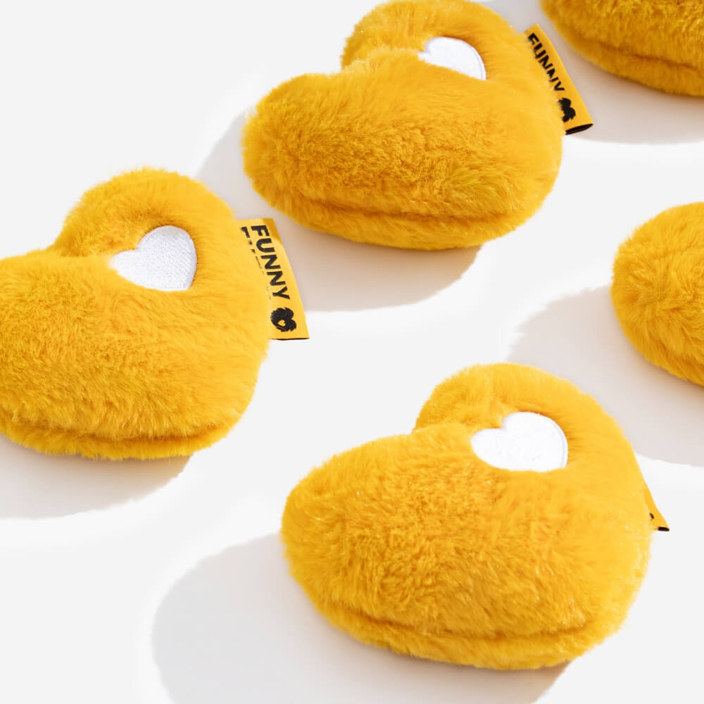 Soft heart-shaped plush dog toy with squeaker, held by a golden retriever