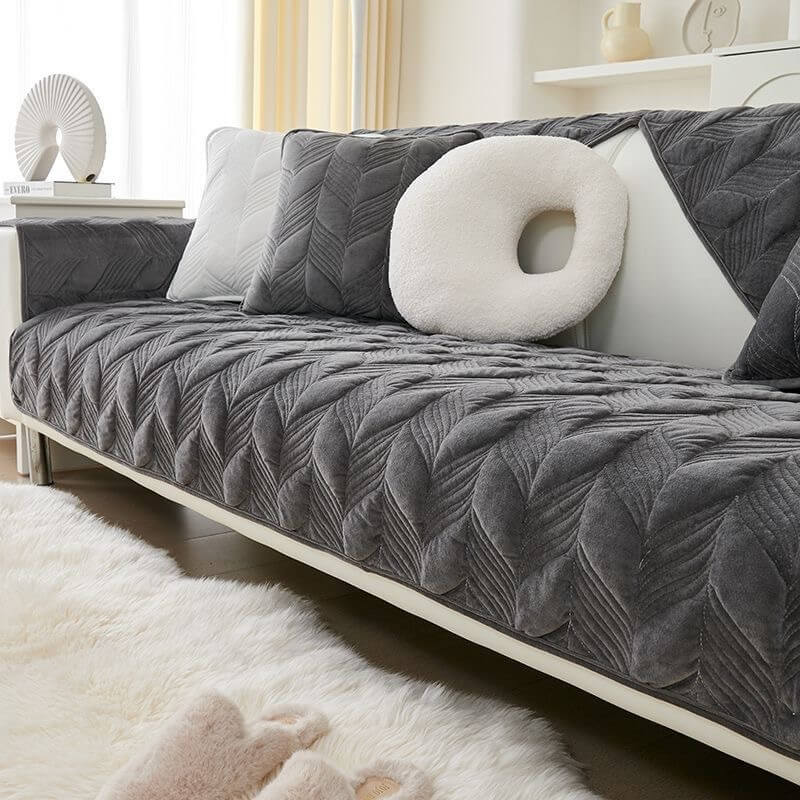 Front view of suede slipcover styled on a modern sofa with light décor accents