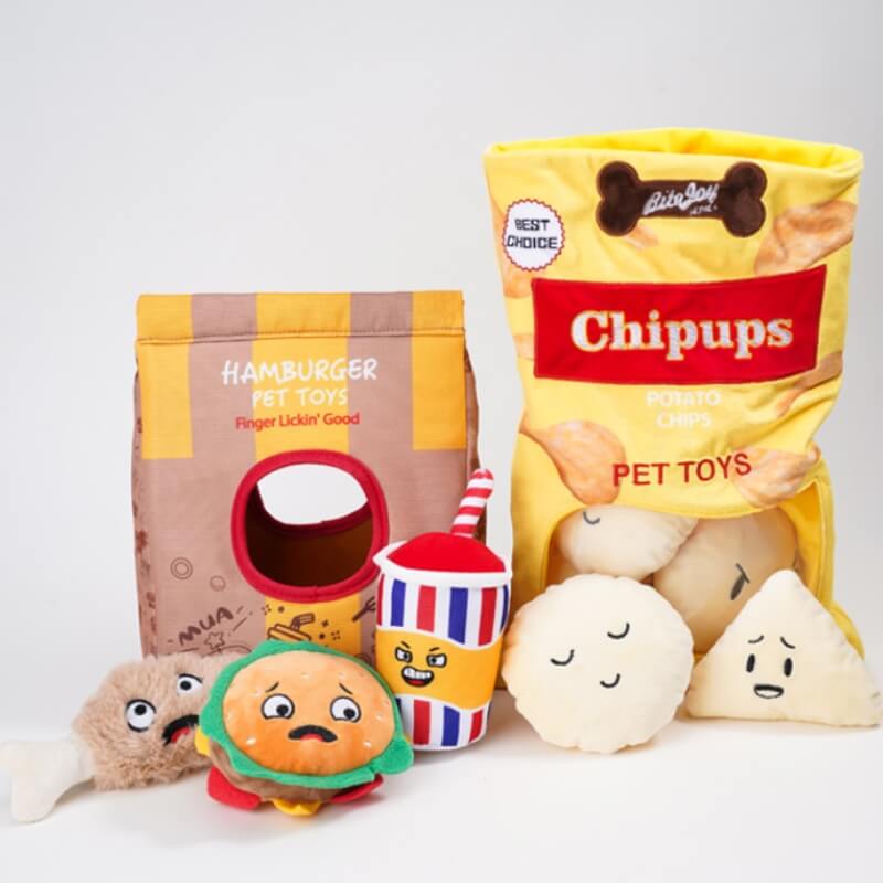 Top-down shot of all plush dog toys arranged: chip bag, burger, soda, and bone, ideal interactive dog toy set.