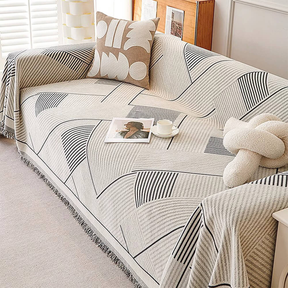 Reversible geometric chenille throw blanket draped over a gray sofa