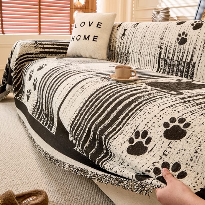 Overhead shot of a soft, textured chenille throw with playful paw prints draped perfectly over a light gray sofa, showing effective pet protection.