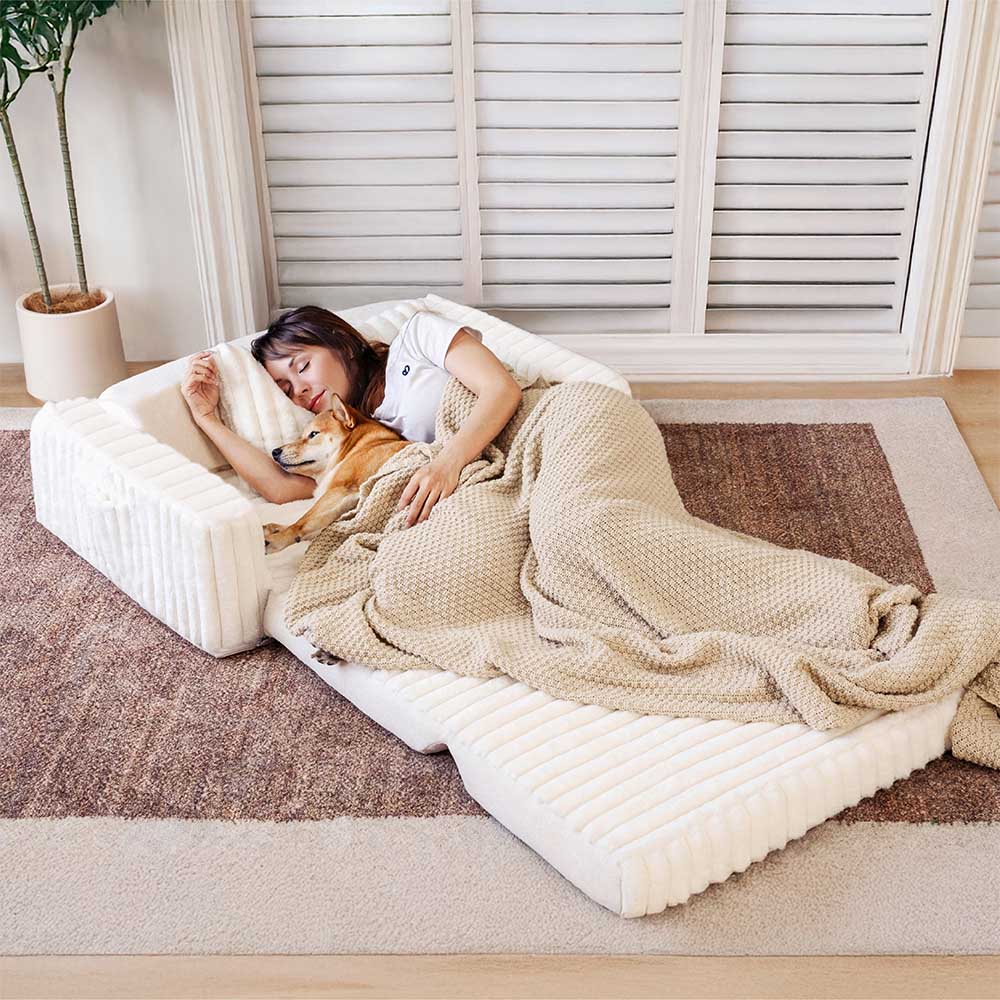 Overhead view of a couple and a large dog comfortably lounging on an open CozyHaven human dog bed with bolster in a living room setting.