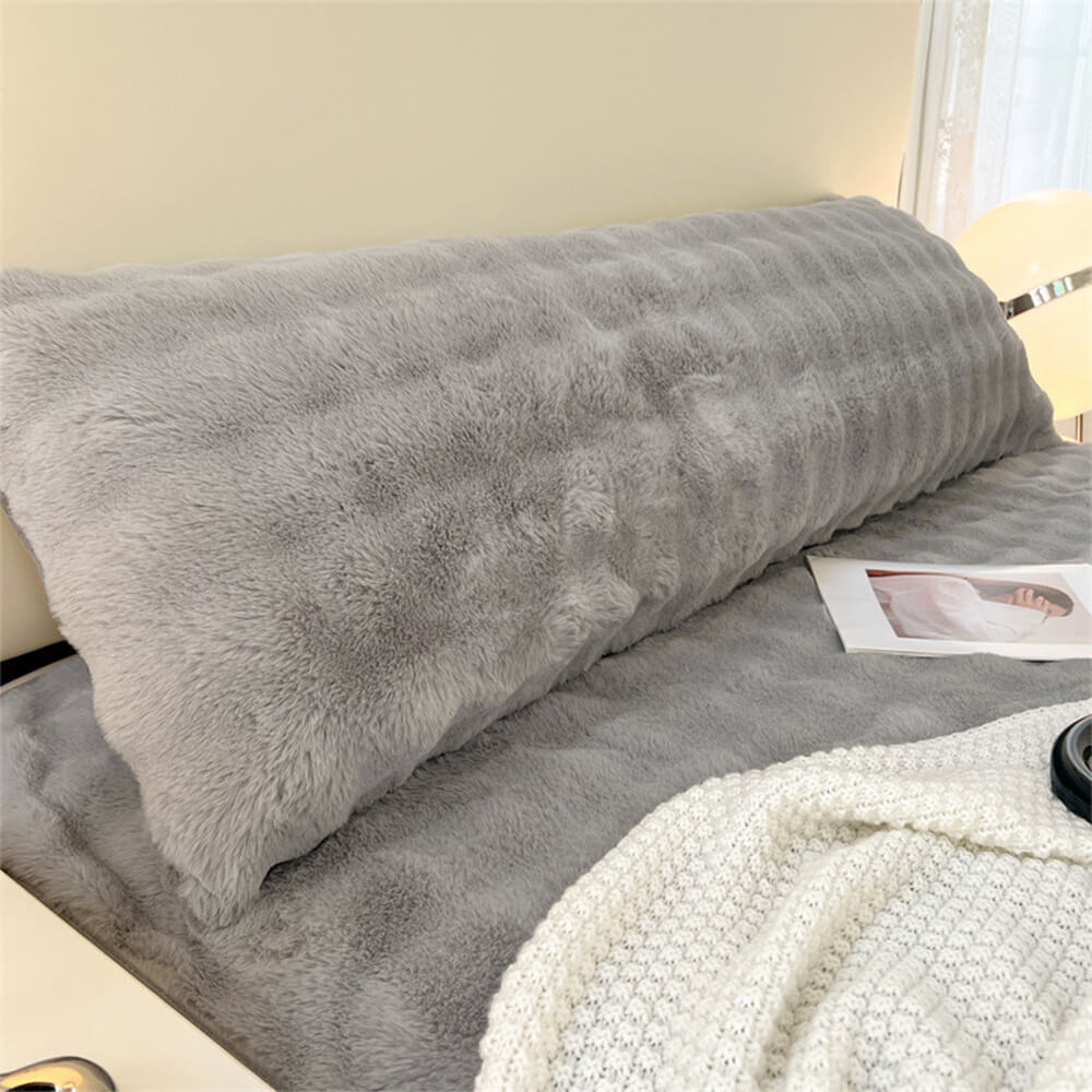 A plush CloudNine extended faux fur headboard pillow in a modern bedroom setting, offering comfortable back support.