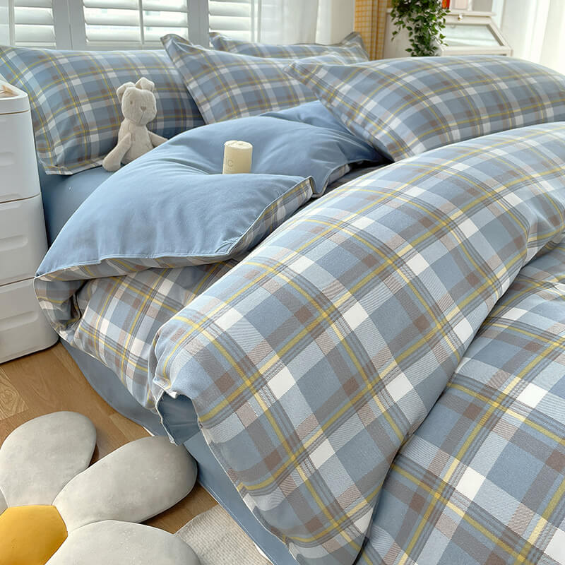 Close-up of plaid bed sheets in a color-block design, draped over a queen bed.
