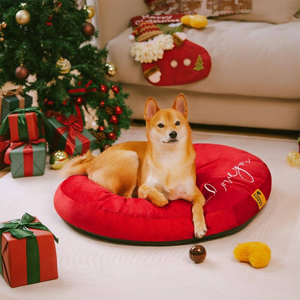 Top-down view of the heart shaped dog bed in red velvet placed beside wrapped gifts