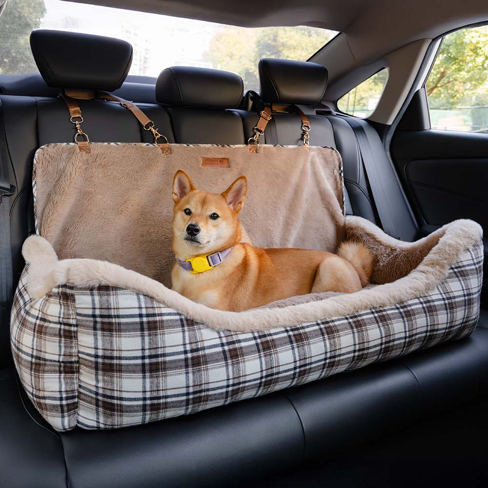 Large fluffy dog in a secure dog booster seat with belt, looking out the car window